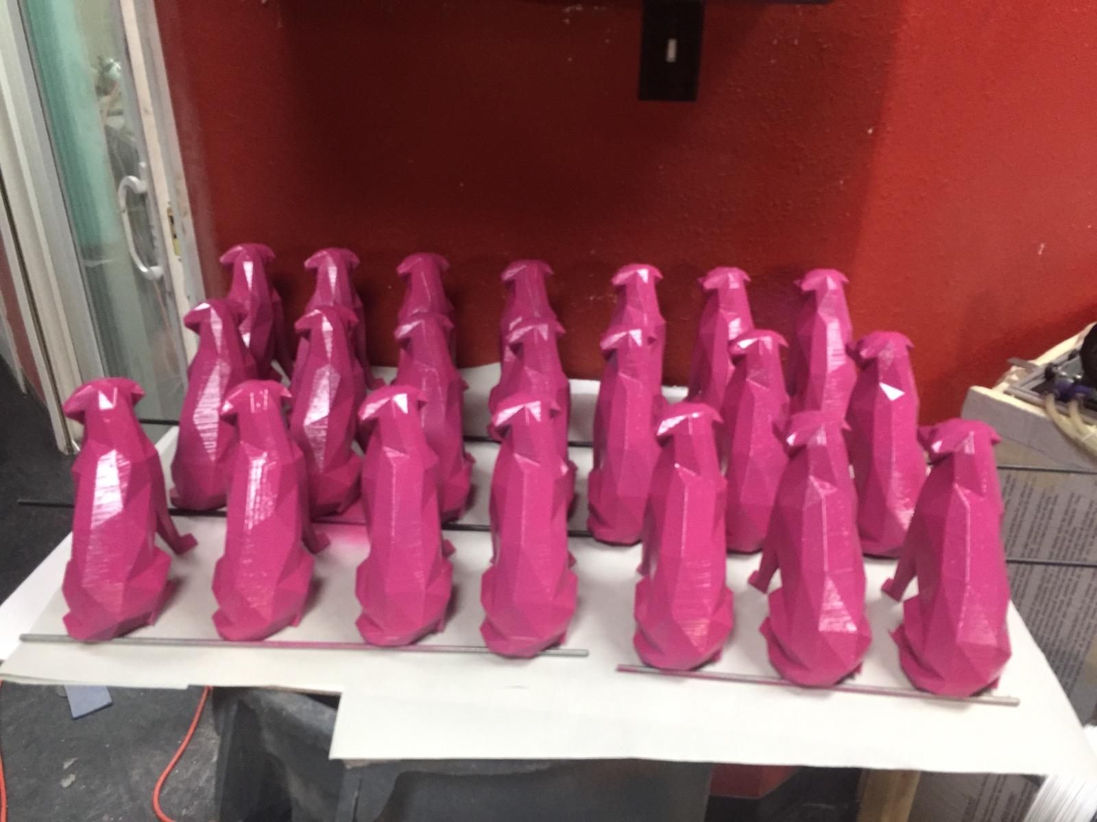 Repeated pink 3D printed parts arranged on a shop table